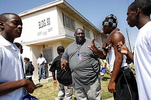 Gang interventionist Michael Cummings, a former Grape Street Crip, talks to kids near the Jordon Downs housing project in South Los Angeles. He is as imposing as a defensive tackle and wields absolute respect in the neighborhood where he grew up. Parents adore him. Gangbangers listen to him.