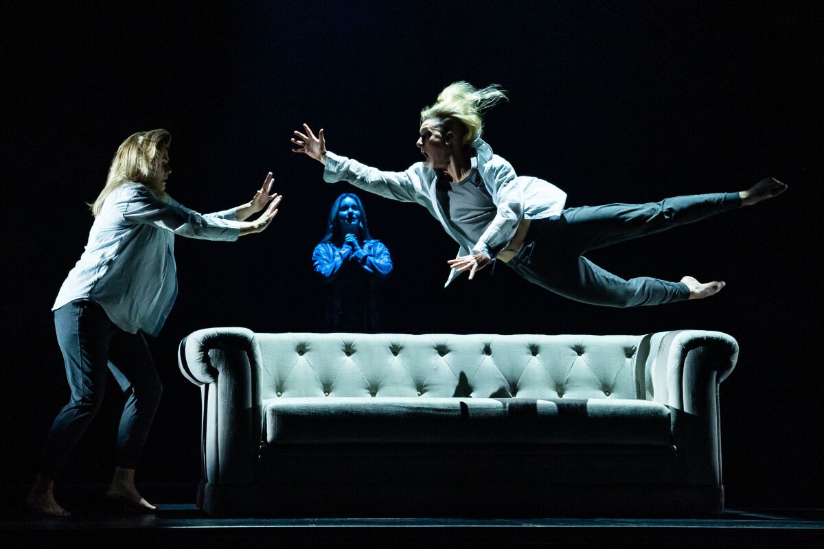 A leaping cast member is midair over a sofa in a scene from the national tour of "Jagged Little Pill."