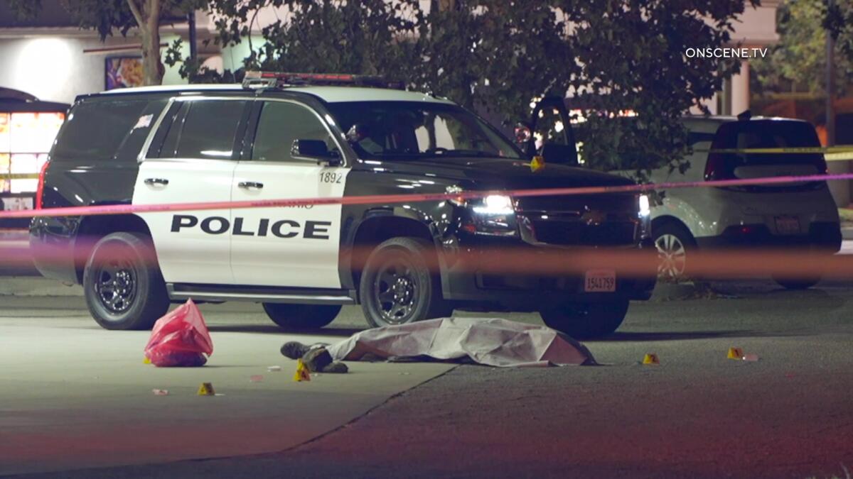 A police cruiser sits behind crime scene tape.