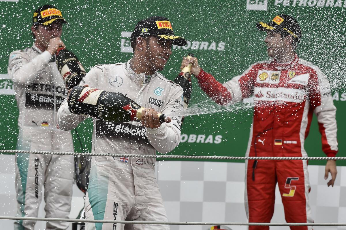 El piloto alemán Nico Rosberg (i) de Mercedes; junto a su compañero británico Lewis Hamilton (c), y el alemán Sebastián Vettel (d), celebran en el podio hoy, domingo 15 de noviembre de 2015, tras el Gran Premio de Formula Uno de Brasil, en el autódromo de Interlagos, en Sao Paulo (Brasil). Rosberg (Mercedes) venció este domingo, por segundo año consecutivo, el Gran Premio de Brasil y se proclamó, a falta de una carrera, subcampeón de la temporada detrás de su compañero, el británico Lewis Hamilton, que cruzó segundo la línea de meta del circuito de Interlagos. EFE/Sebastiao Moreira ** Usable by HOY, FL-ELSENT and SD Only **