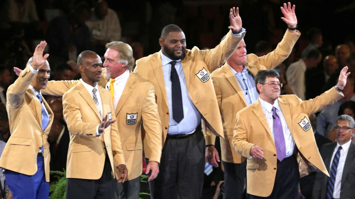 The newest members of the Pro Football Hall of Fame -- from left, Tony Dungy, Marvin Harrison, Kevin Greene, Orlando Pace, Brett Favre, and Edward J. Debartolo, Jr. -- wave to the crowd at the induction dinner Thursday after receiving their gold jackets.
