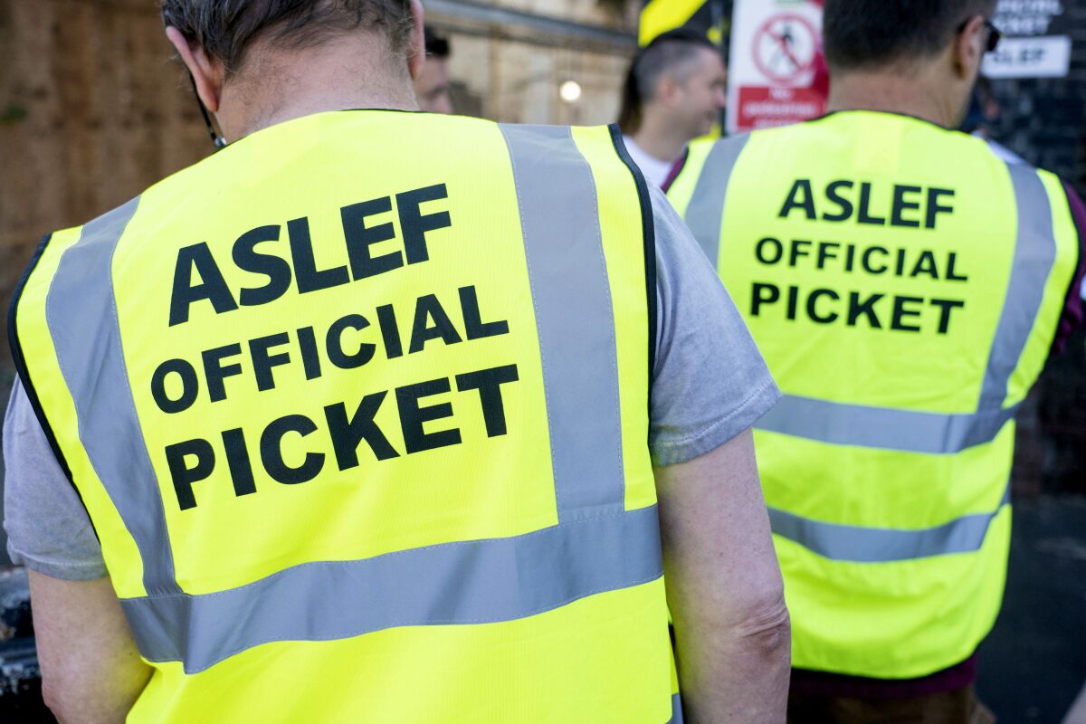 Miembros del sindicato Sociedad Asociada de Ingenieros Ferroviarios y Bomberos efectúan una huelga de 24 horas en la estación Willesden Junction en demanda de un alza salarial, en Londres, el sábado 13 de agosto de 2022. (Dominic Lipinski/PA vía AP)
