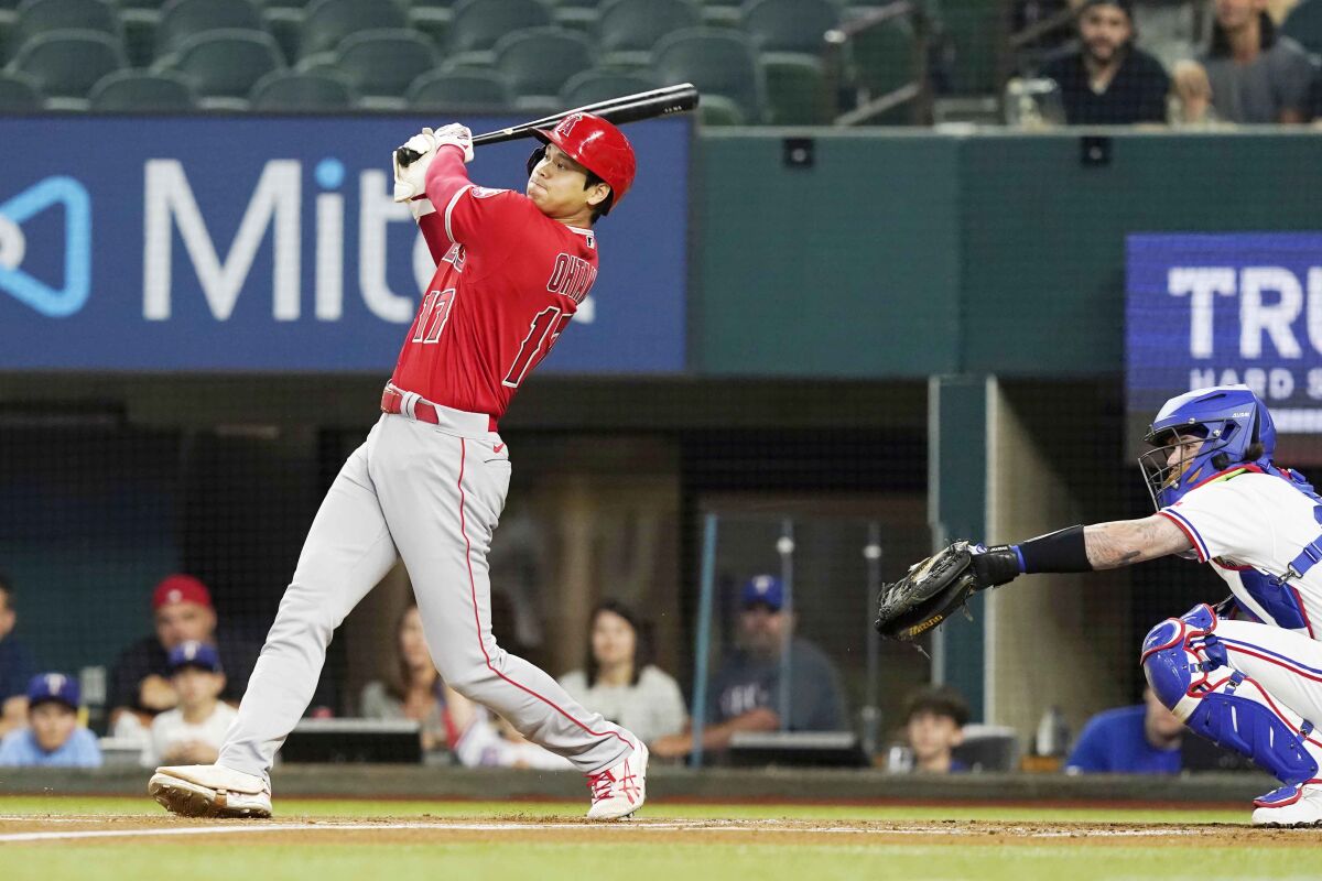 Angels Shohei Ohtani hits a double in front of Texas Rangers catcher Jonah Heim.