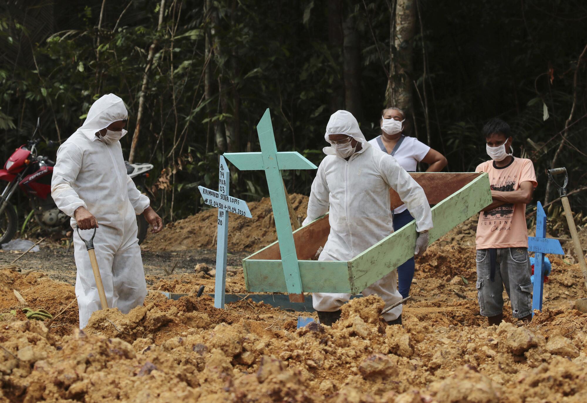 Funeral workers in protective gear prepare a grave for a COVID-19 victim at the Nossa Senhora Aparecida cemetery in Brazil.