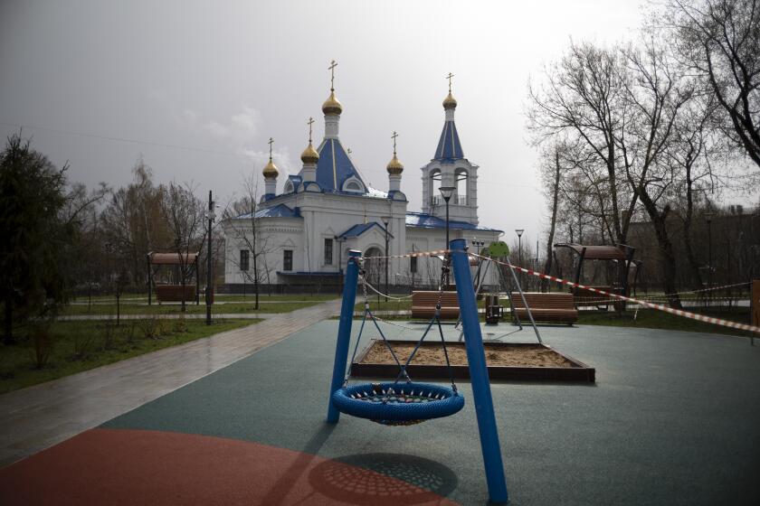 Una cinta acordona un parque infantil vacío en una iglesia ortodoxa, cerrada al culto por la pandemia del coronavirus, en Moscú, Rusia, el 18 de abril de 2020. (AP Foto/Alexander Zemlianichenko)