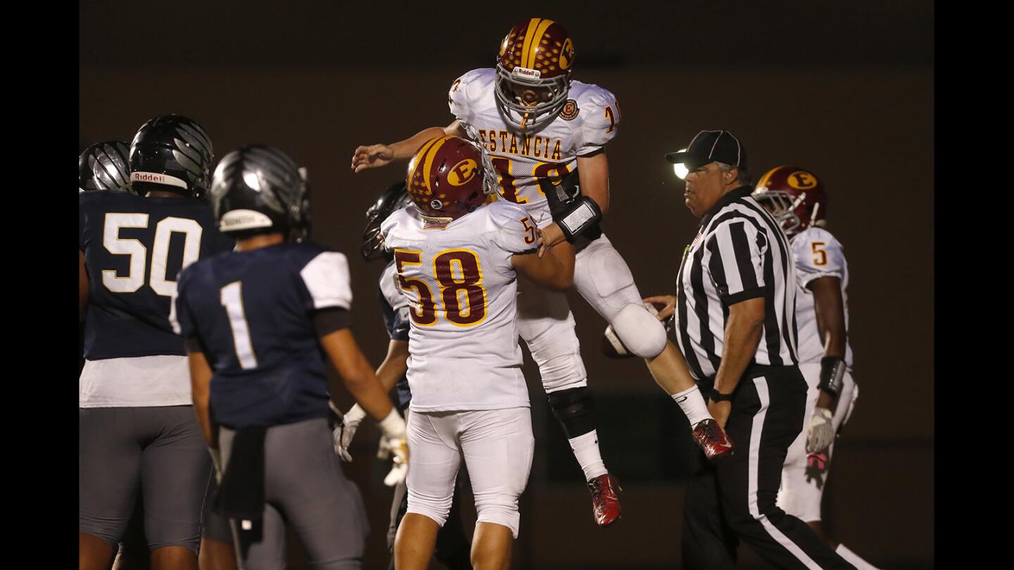 Estancia High running back Trevor Pacheco is lifted up by linebacker Raul Gonzalez (58) after rushing for a second touchdown against Calvary Chapel during the first half in an Orange Coast League game at Segerstrom High on Thursday, Sept. 27.