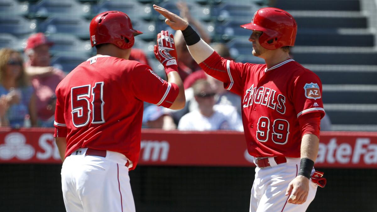Angels teammates Ji-Man Choi (51) and Taylor Ward (99) celebrate after scoring against the Cubs on a single by David Fletcher in the eighth inning Sunday.