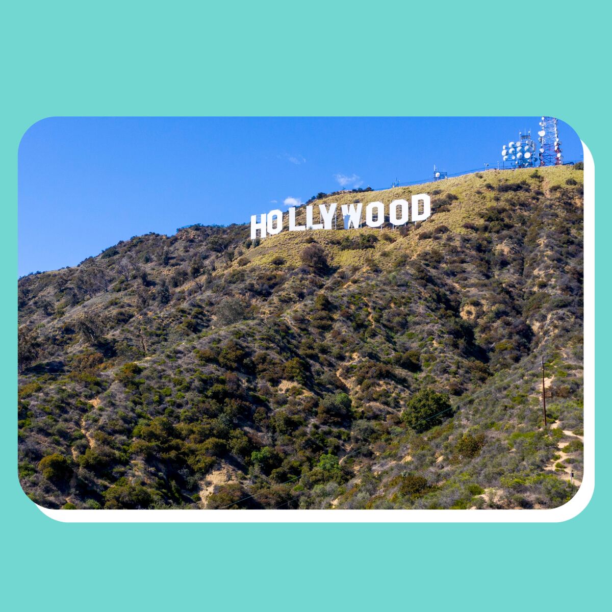 Large white letters on a green hillside spell out "Hollywood," with blue sky in the background.