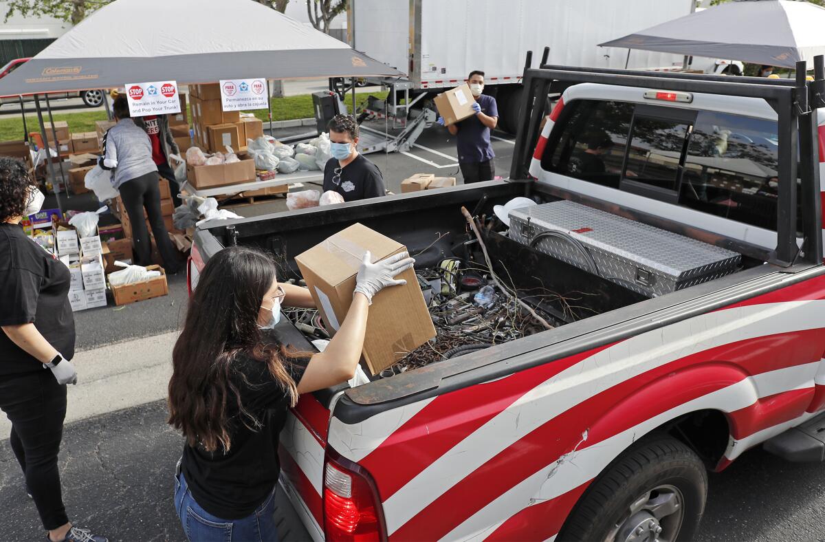 Volunteers load boxes of food into the back of a pickup truck during a drive-through food distribution at Colette's Children's Home on Saturday morning. The Huntington Beach-based nonprofit provides housing and supportive services to homeless women and children throughout Orange County.