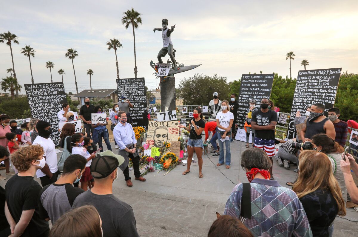A large crowd gathered at the "Cardiff Kook" statue in Encinitas on Tuesday to demonstrate for racial justice and reform.