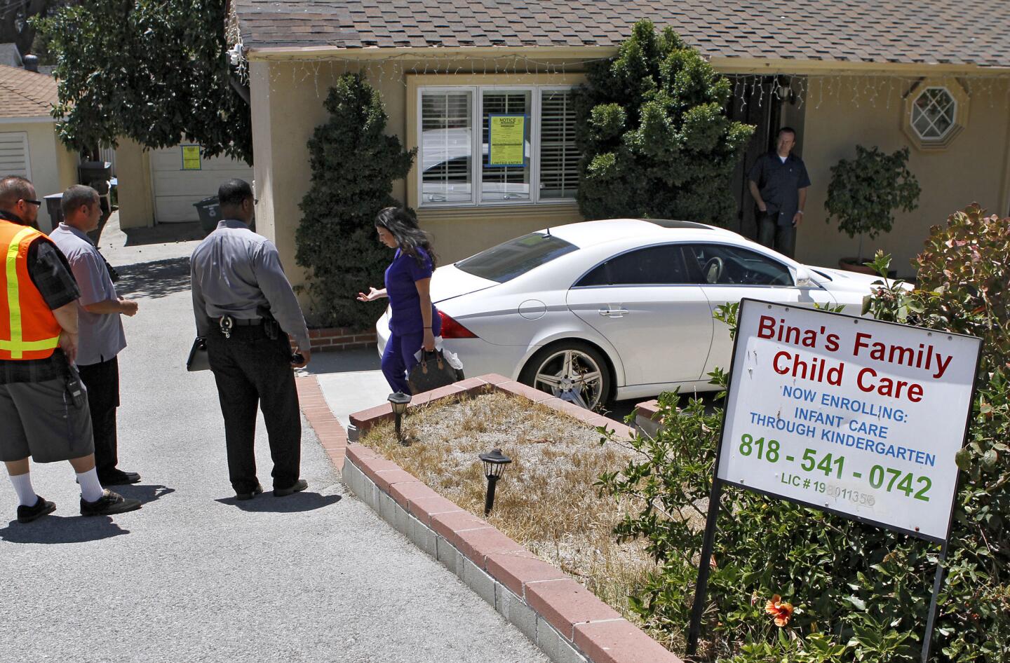 A woman who showed up to get some things out of the house at 3210 Orange Ave. speaks with Glendale Neighborhood Services and Glendale Police Dept. officials after Bina's Family Child Care was shut down at the home in La Crescenta on Wednesday, August 14, 2013. Officials posted a sign that said "LIMITED ENTRY. Occupancy Prohibited. No living, sleeping, cooking allowed. Entry limited for purposes of repair only."