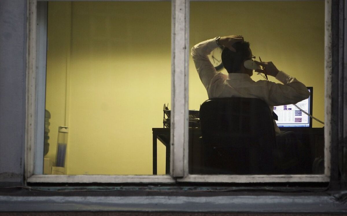 A man talks on the phone while working on a computer
