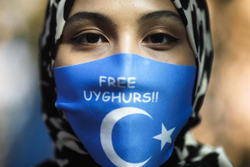 FILE - A woman wears a face mask reading 'Free Uyghurs' as she attends a protest during the visit of Chinese Foreign Minister Wang Yi in Berlin, Germany, Tuesday, Sept. 1, 2020. Experts at the U.N. labor agency have called out China on work conditions faced by Uyghurs and other Muslim minorities in the western Xinjiang region, decrying signs of “coercive measures” that deprive workers of the free choice in job-selection and calling for Beijing to provide more information about how it’s respecting their rights. (AP Photo/Markus Schreiber, File)