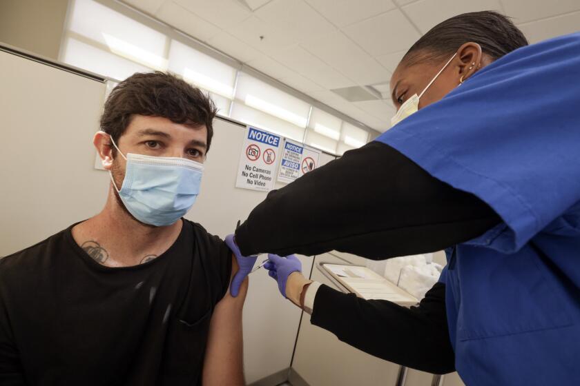SAN DIEGO, CA - SEPTEMBER 27, 2023: Rodrigo Costa receives the new updated Covid 19 vaccine from Licensed Vocational Nurse, Tashiya Miller at the North Central Public Health Center in San Diego on Wednesday, September 27, 2023. (Hayne Palmour IV / For The San Diego Union-Tribune)