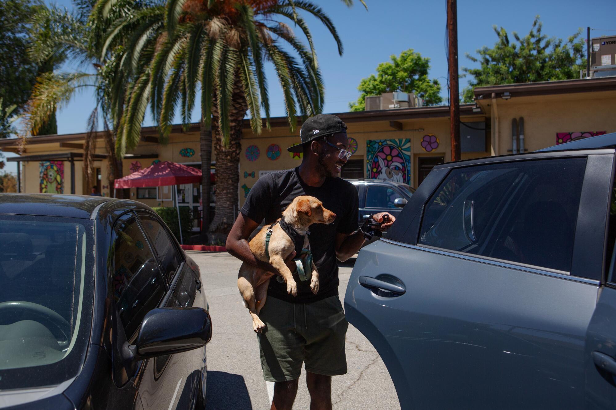 Kavar McDaniel carries his newly adopted dog to his car outside a Los Angeles County Animal Care and Control shelter. 