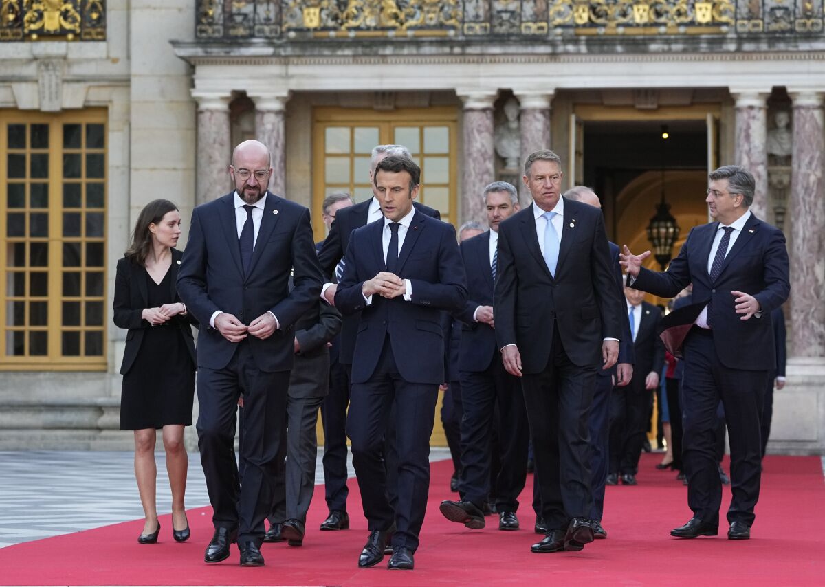 French President Emmanuel Macron, center, speaks with European Council President Charles Michel, center left, as they walk to a group photo at an EU summit at the Chateau de Versailles, in Versailles, west of Paris, Thursday, March 10, 2022. European Union leaders on Thursday will focus on how to help Ukraine in its war with Russia, but the measures discussed are expected to stop short of fulfilling the country's hopes it can soon join the bloc. (AP Photo/Michel Euler)