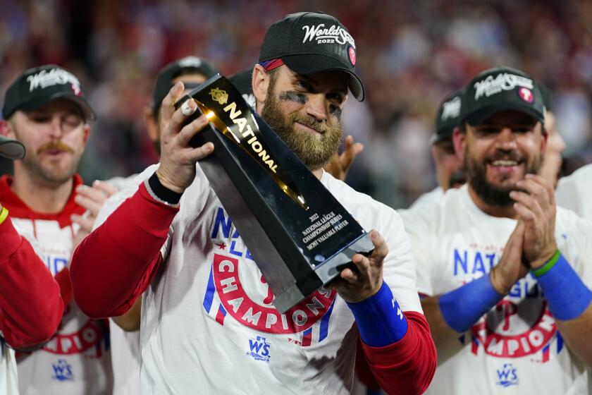 Philadelphia Phillies designated hitter Bryce Harper celebrates with the trophy after winning the baseball.