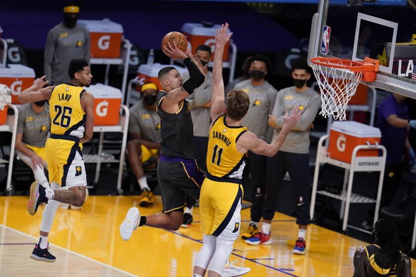 Los Angeles Lakers forward Kyle Kuzma, center, shoots between Indiana Pacers guard Jeremy Lamb (26) and Domantas Sabonis (11) during the second half of an NBA basketball game Friday, March 12, 2021, in Los Angeles. (AP Photo/Marcio Jose Sanchez)