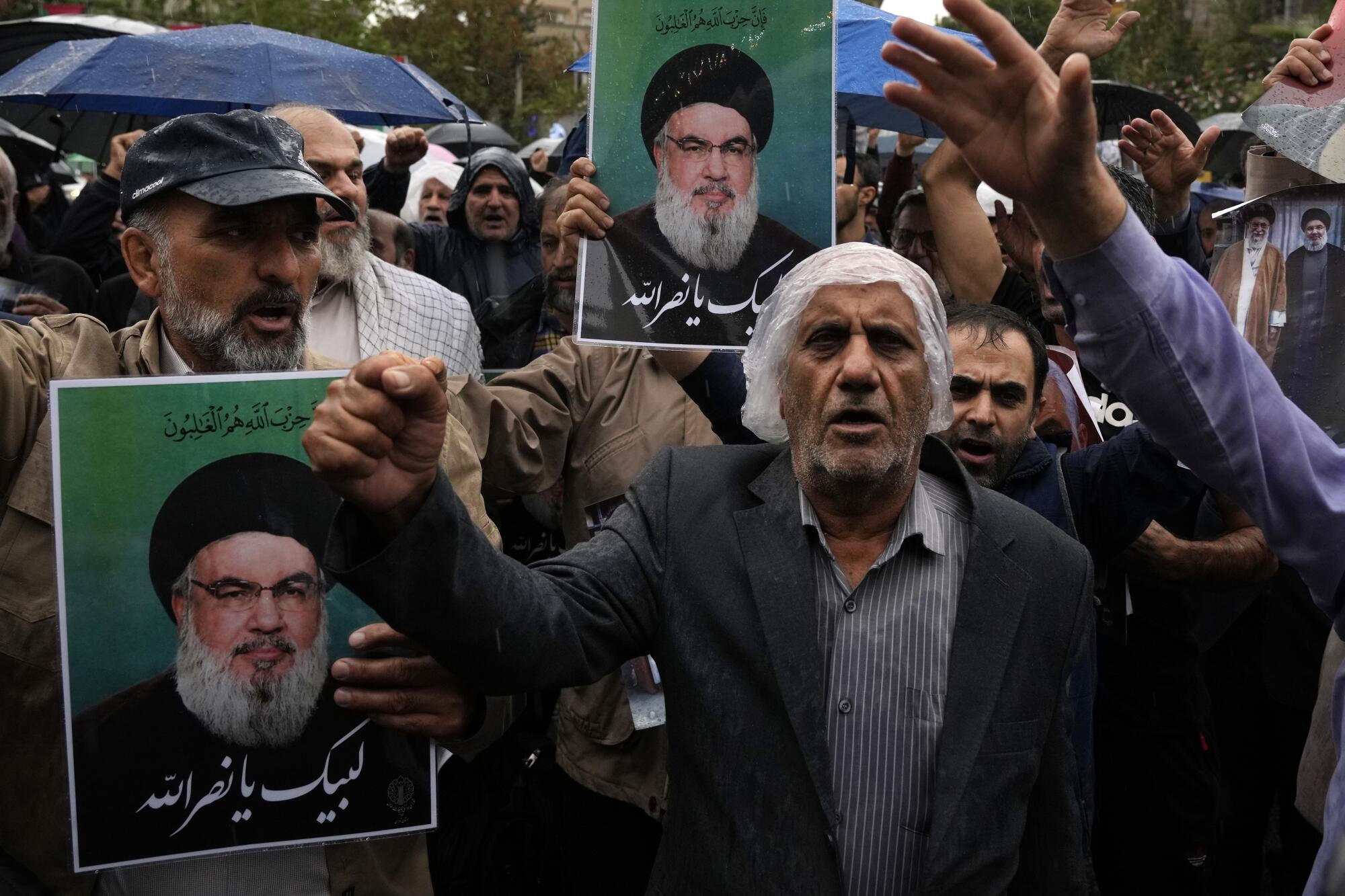 Demonstrators holding portraits of Hezbollah's slain leader chant slogans 