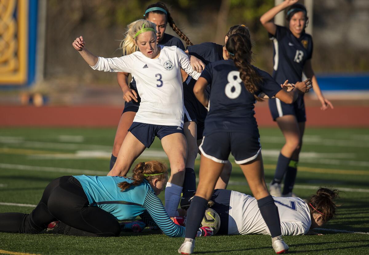 Marina goalkeeper Carly Miles, left, dives for a loose ball as Newport Harbor's Reese Bodas (3) attempts to knock it free in a Wave League match on Tuesday.