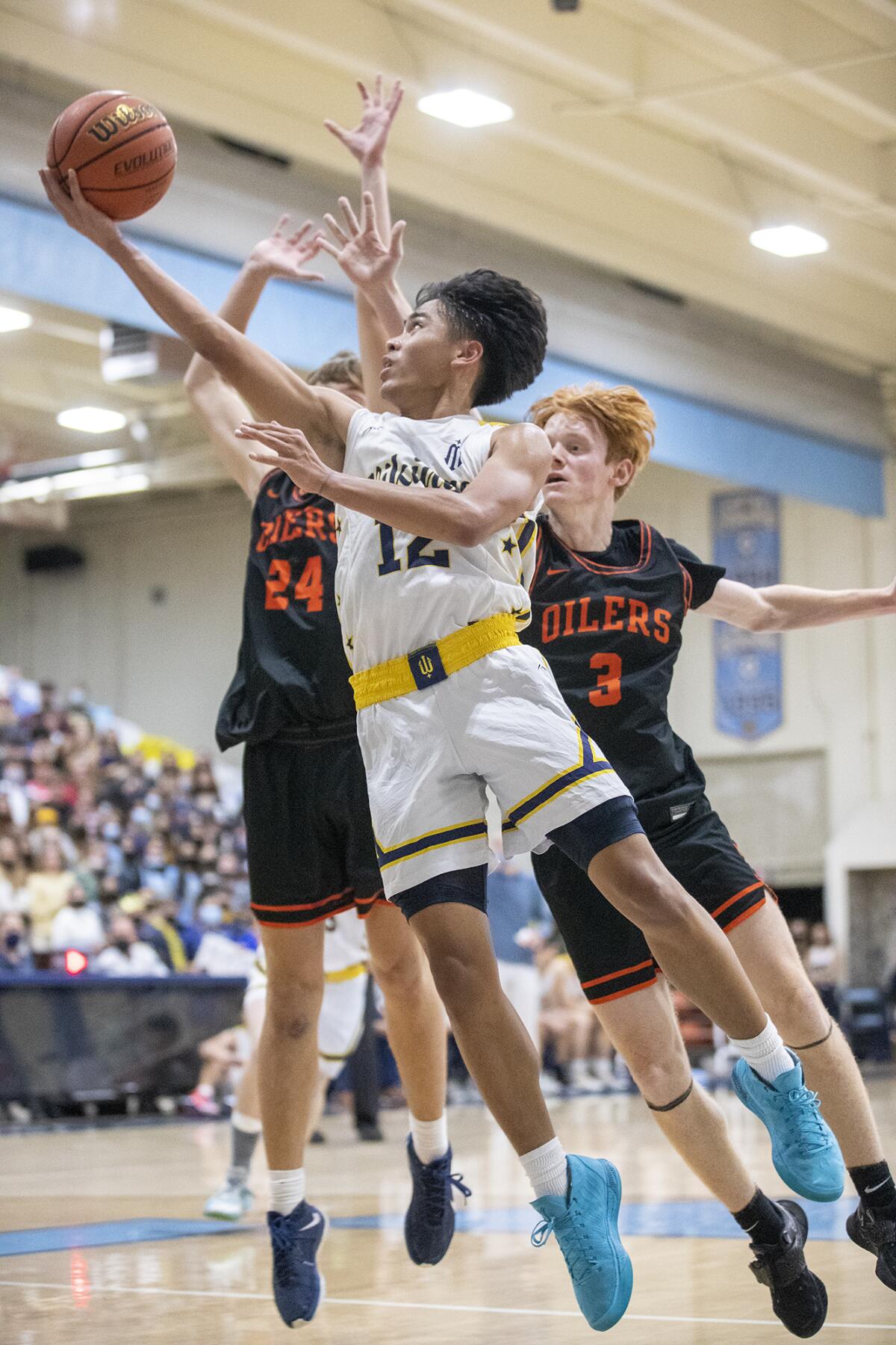 Marina's Kylle Magdangal shoots a layup against Huntington Beach's Kyle Bennett, left, and Tyler Mangold.