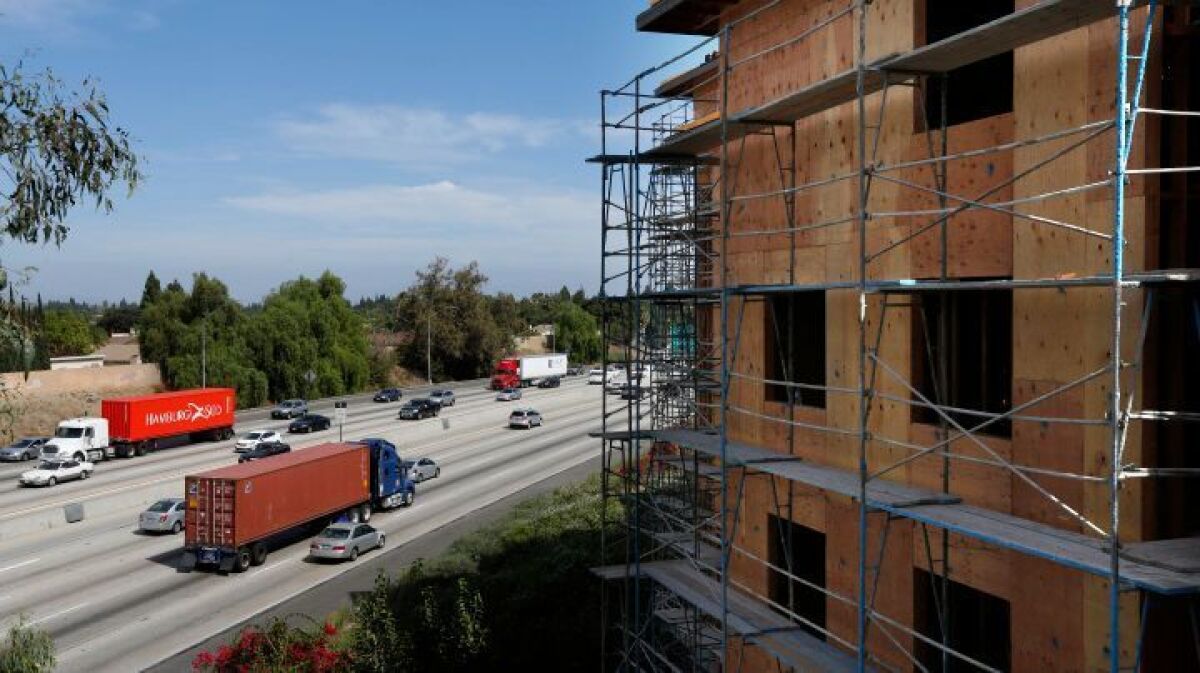 Cars and trucks pass by a 198-unit luxury apartment complex under construction in 2015 next to the 91 Freeway at Artesia Boulevard in Cerritos.