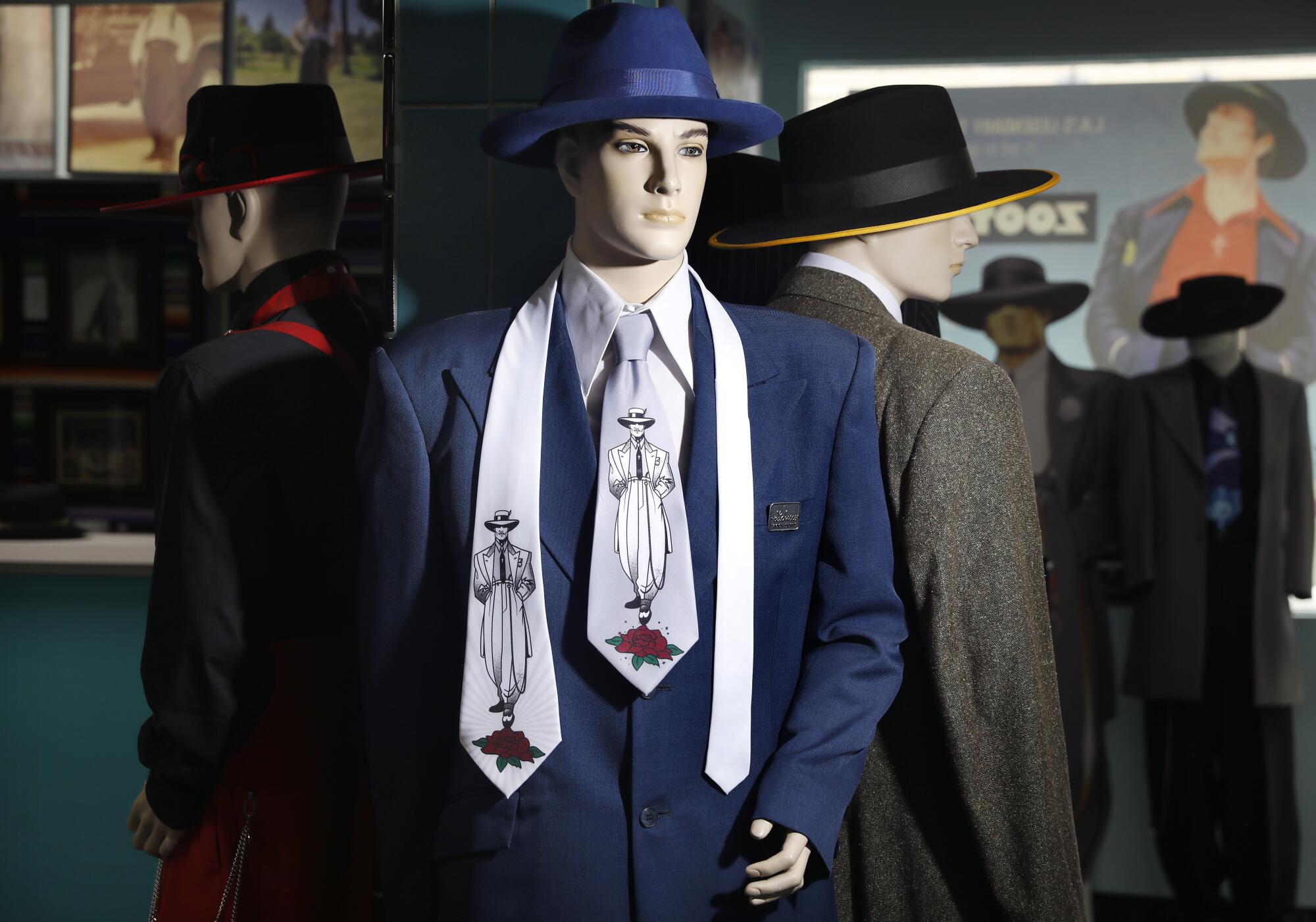 A mannequin sports a blue zoot suit and a wide-brim hat, as well as a tie bearing an image of a zoot suiter.