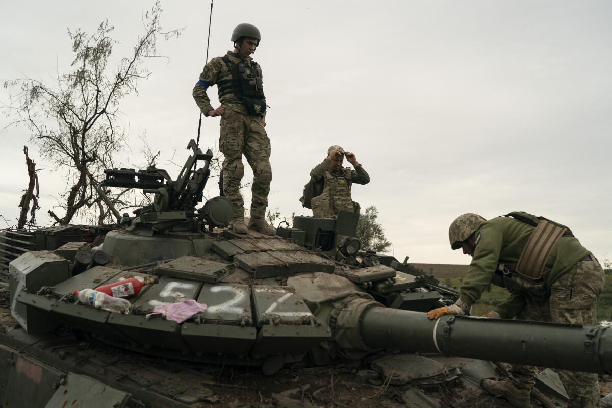 Servicemen atop a destroyed tank