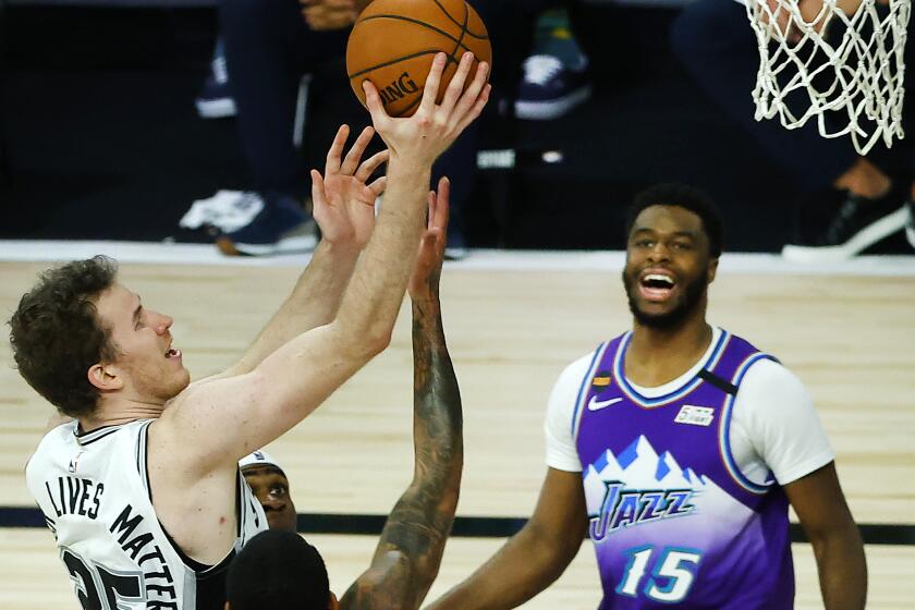 San Antonio Spurs' Jakob Poeltl drives to the basket between Utah Jazz's Jordan Clarkson, left, and Emmanuel Mudiay.
