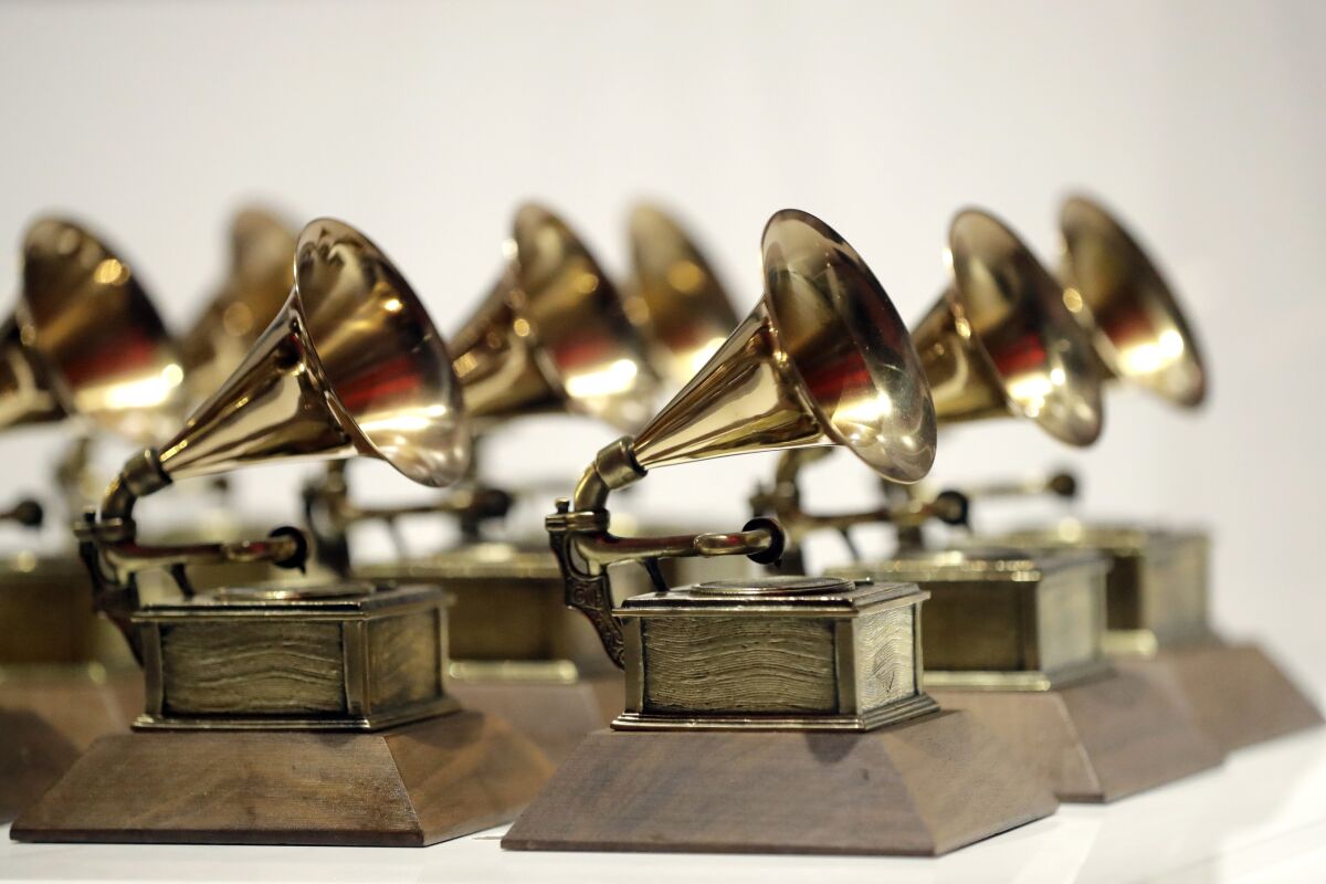 Multiple golden Grammy Awards with wooden bases sit in neat rows