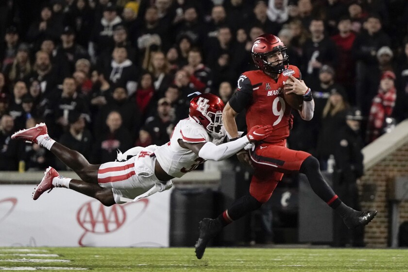 Cincinnati quarterback Desmond Ridder (9) is tackled by Houston's Gervarrius Owens during the second half of the American Athletic Conference championship NCAA college football game Saturday, Dec. 4, 2021, in Cincinnati. (AP Photo/Jeff Dean)