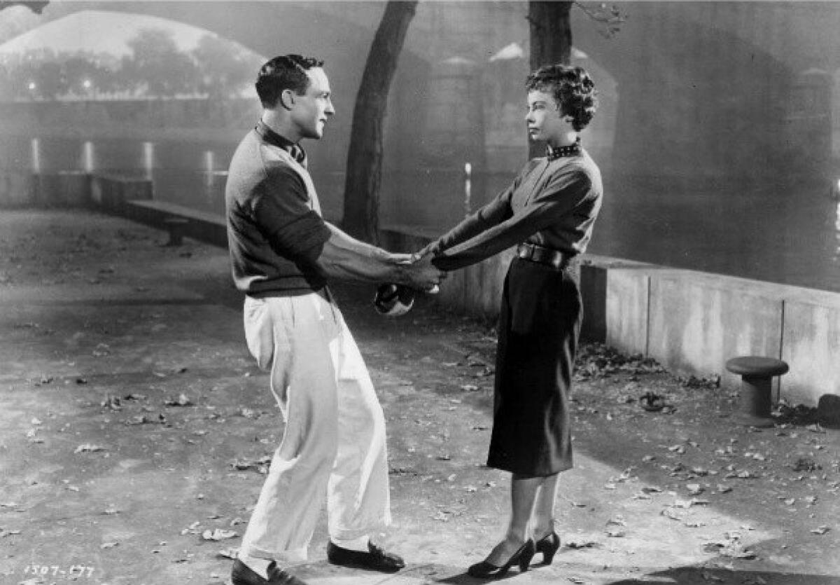 Gene Kelly and Leslie Caron holding hand in "An American in Paris."