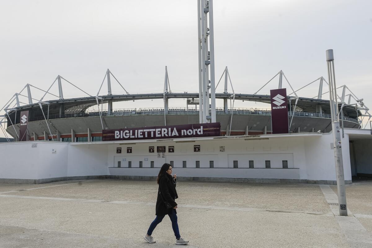 A woman walks by the desert Olympic stadium in Turin Sunday, Feb. 23, 2020. Torino’s match at home to Parma was postponed hours before kickoff on Sunday, following new cases the coronavirus in Piedmont. (Nicolò Campo/LaPresse via AP)