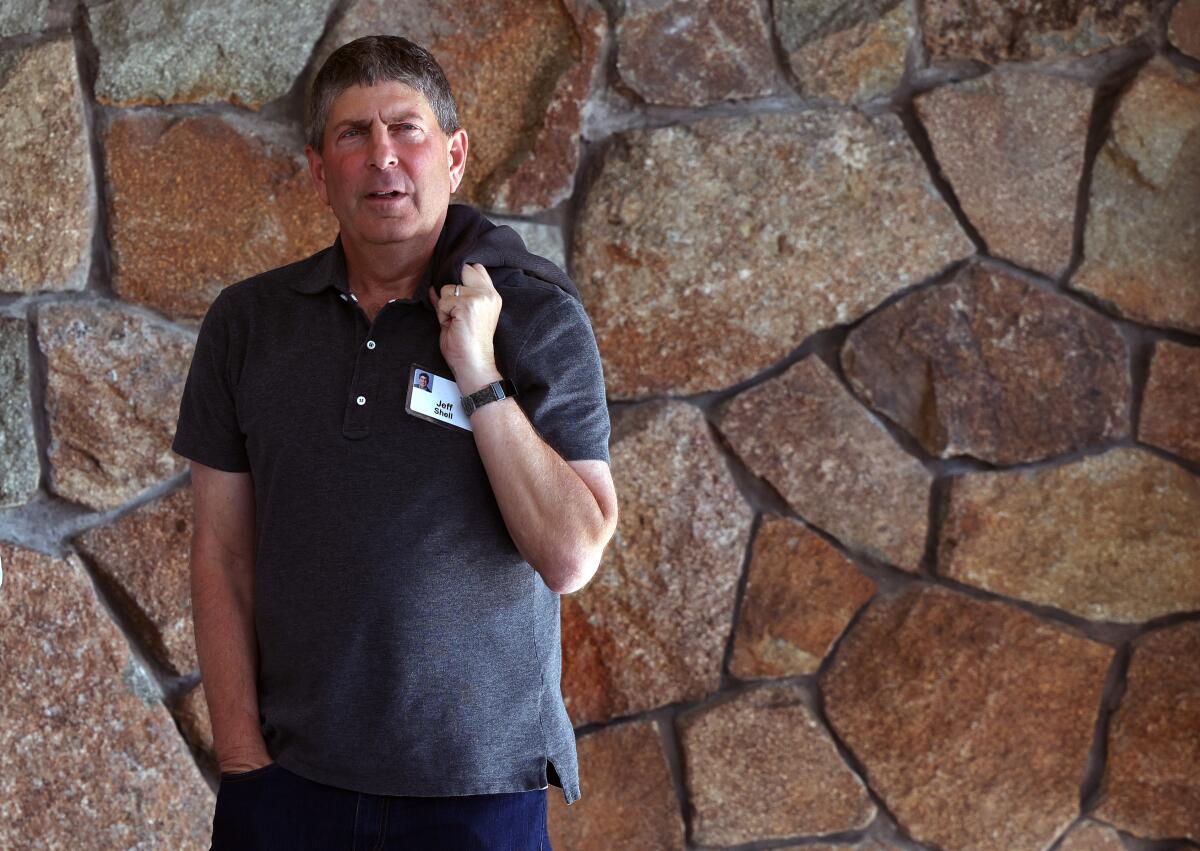 Former NBCUniversal Chief Executive Jeff Shell, wearing a short-sleeved shirt, stands against a stone wall.