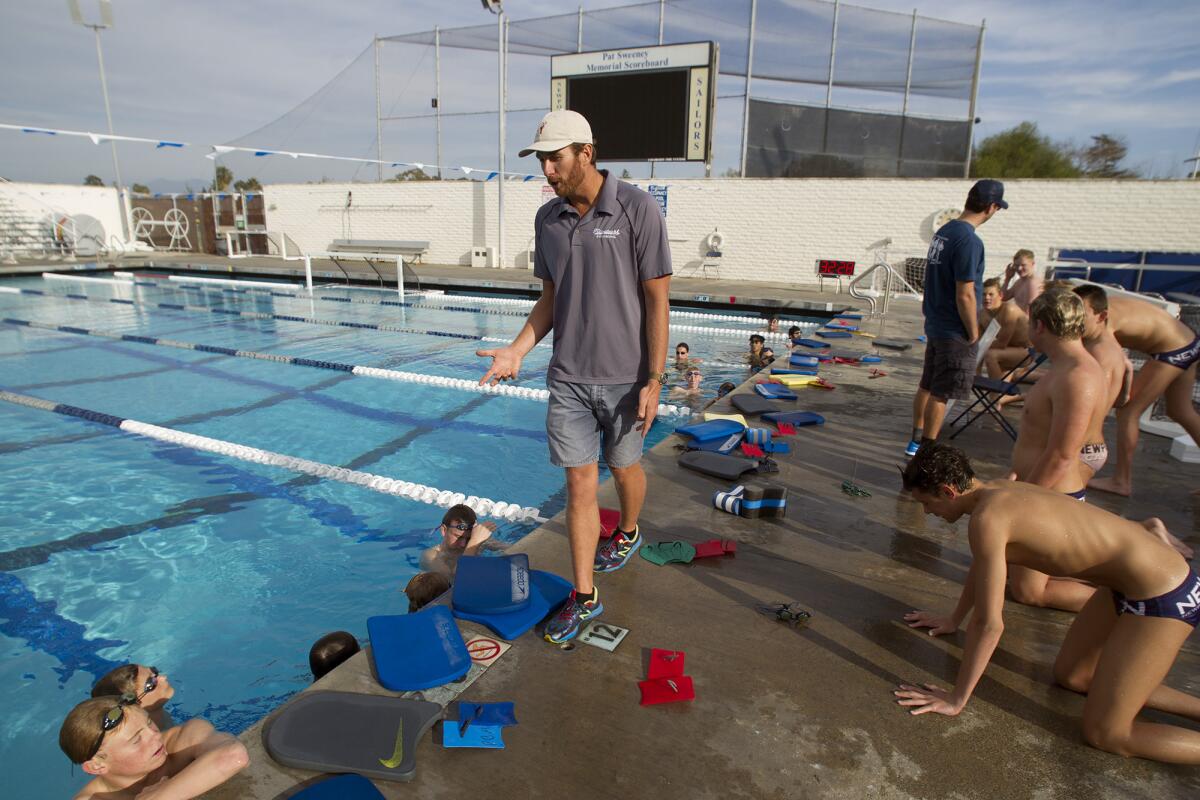 Five-time Olympic gold medalist Aaron Peirsol, center, addresses the team during his first practice as head coach of the Newport Harbor High boys' swim team on Thursday.