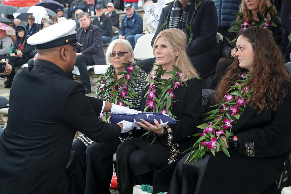 Don MacAllister's daughter, Gayle, accepts an American flag from the U.S. Navy.