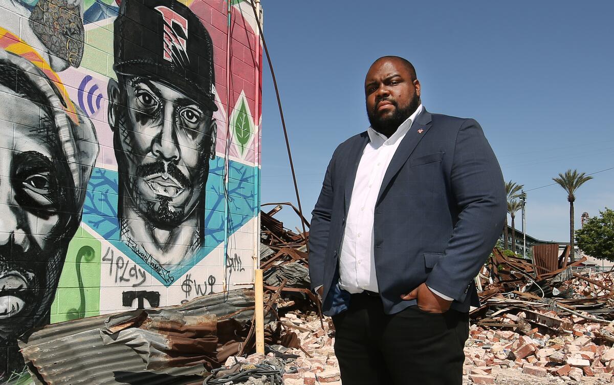 Lourin Hubbard standing amid rubble next to a mural.