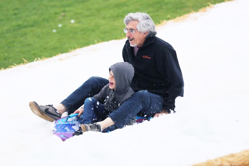 Ethan Fisher and his grandfather, Milt Fisher, sledding down the snow hill.