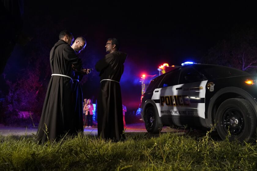Priests gather near the scene where officials say dozens of people have been found dead and multiple others were taken to hospitals with heat-related illnesses after a semitrailer containing suspected migrants was found, Monday, June 27, 2022, in San Antonio. (AP Photo/Eric Gay)