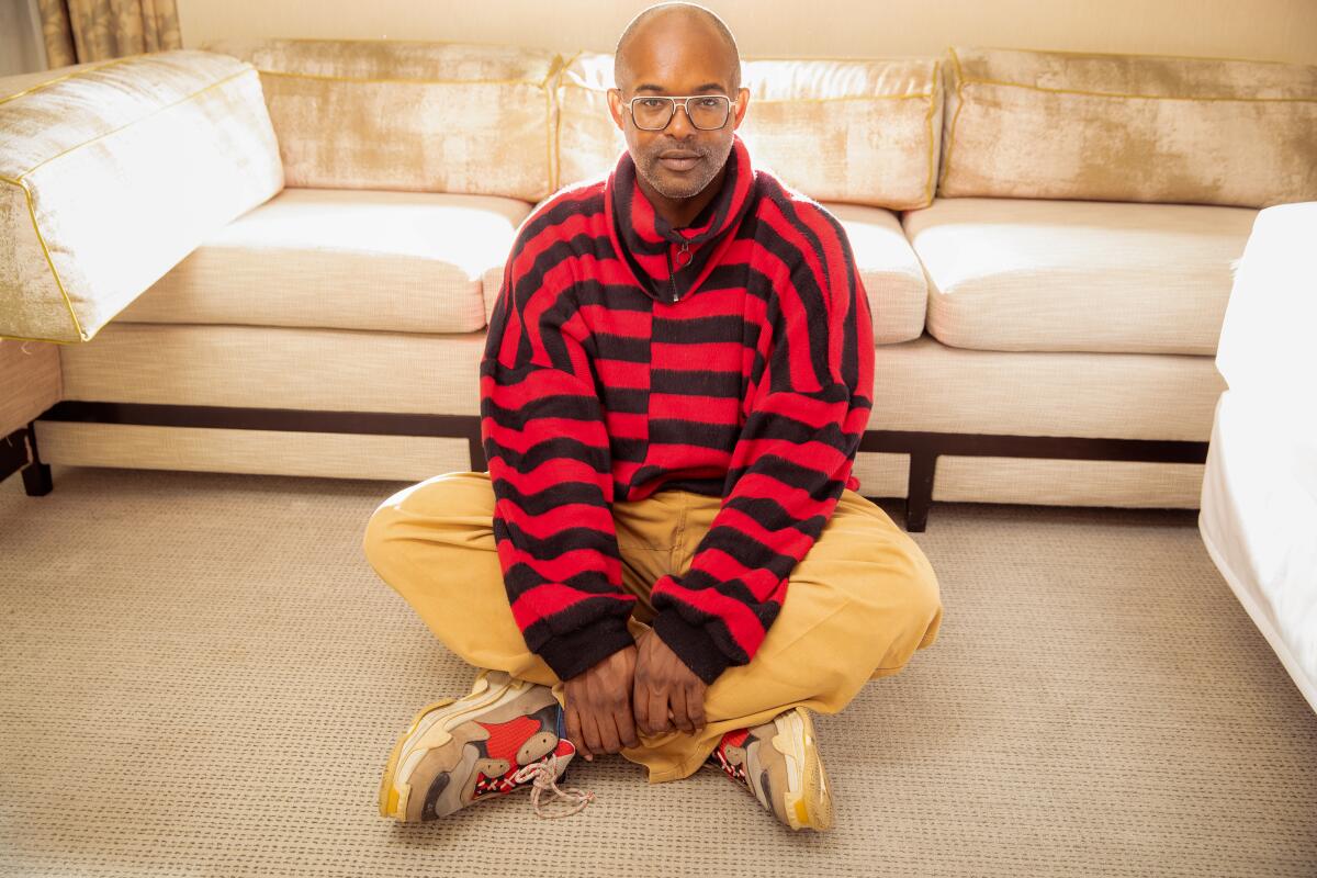 Elegance Bratton sits on the rug, leaning against a couch for a portrait.