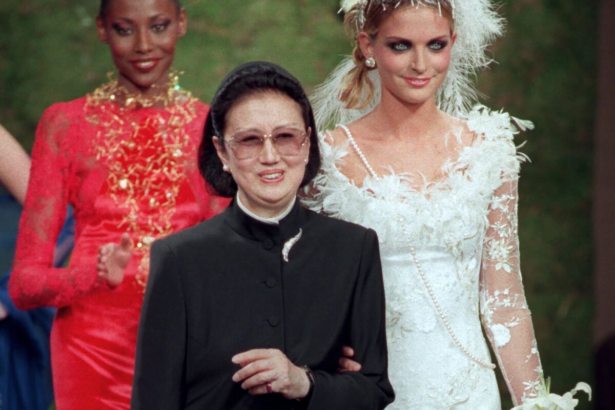 FILE - Japanese fashion designer Hanae Mori, center, is applauded by models after the presentation of her 1997-98 fall-winter haute couture collection presented in Paris, July 9, 1997. Mori, known for her elegant signature butterfly motifs, has died, according to local media reports. She was 96. (AP Photo/Michel Lipchitz, File)