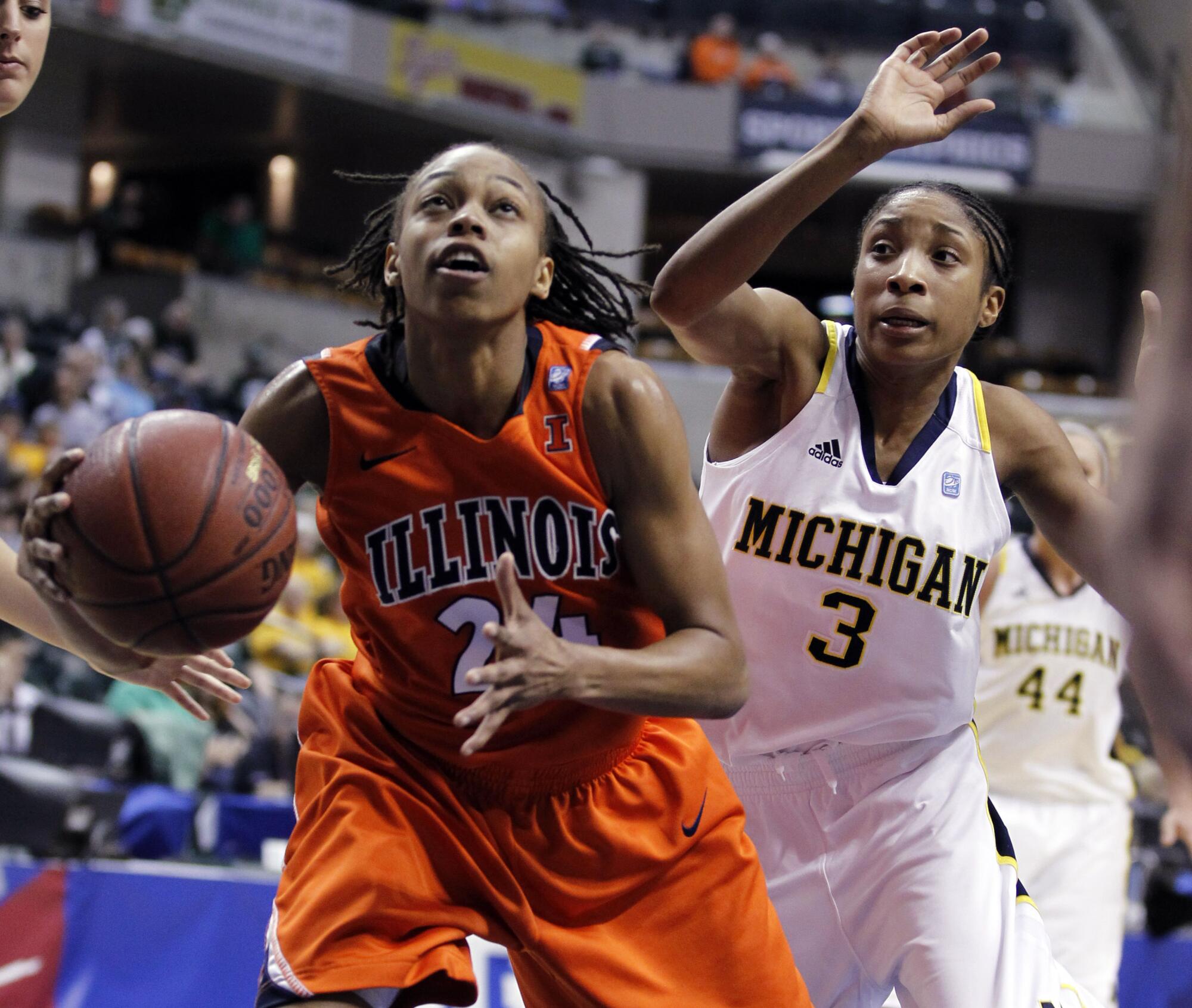 Illinois guard Adrienne Godbold, left, grabs a rebound and looks to shoot as Michigan guard Veronica Hicks defends