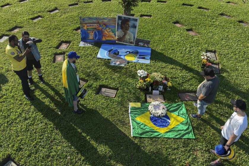 Aficionados se reúnen en la tumba del fallecido piloto brasileo Ayrton Senna al recordar el 30mo aniversario de su muerte, en el cementerio de Morumbí en Sao Paulo, el 24 de mayo de 2024. (AP Foto/Andre Penner)