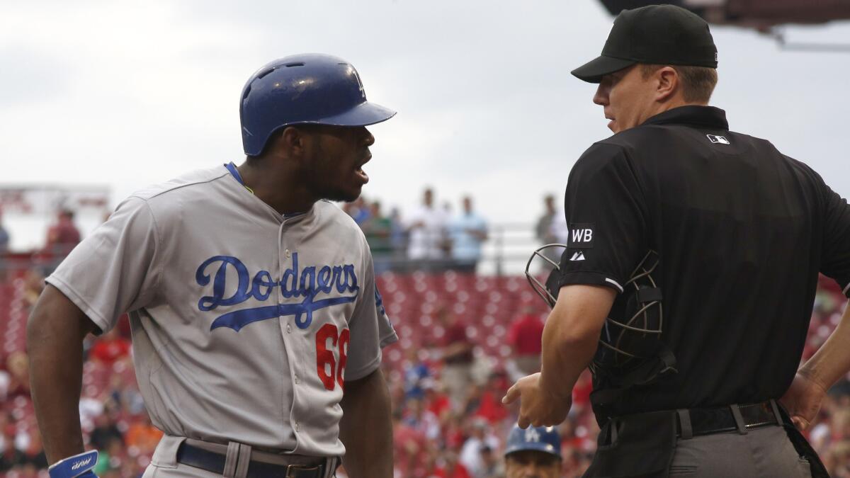 Dodgers right fielder Yasiel Puig, left, argues with home plate umpire Seth Buckminster after striking out during the first inning of the Dodgers' 5-0 loss to the Cincinnati Reds on Wednesday.