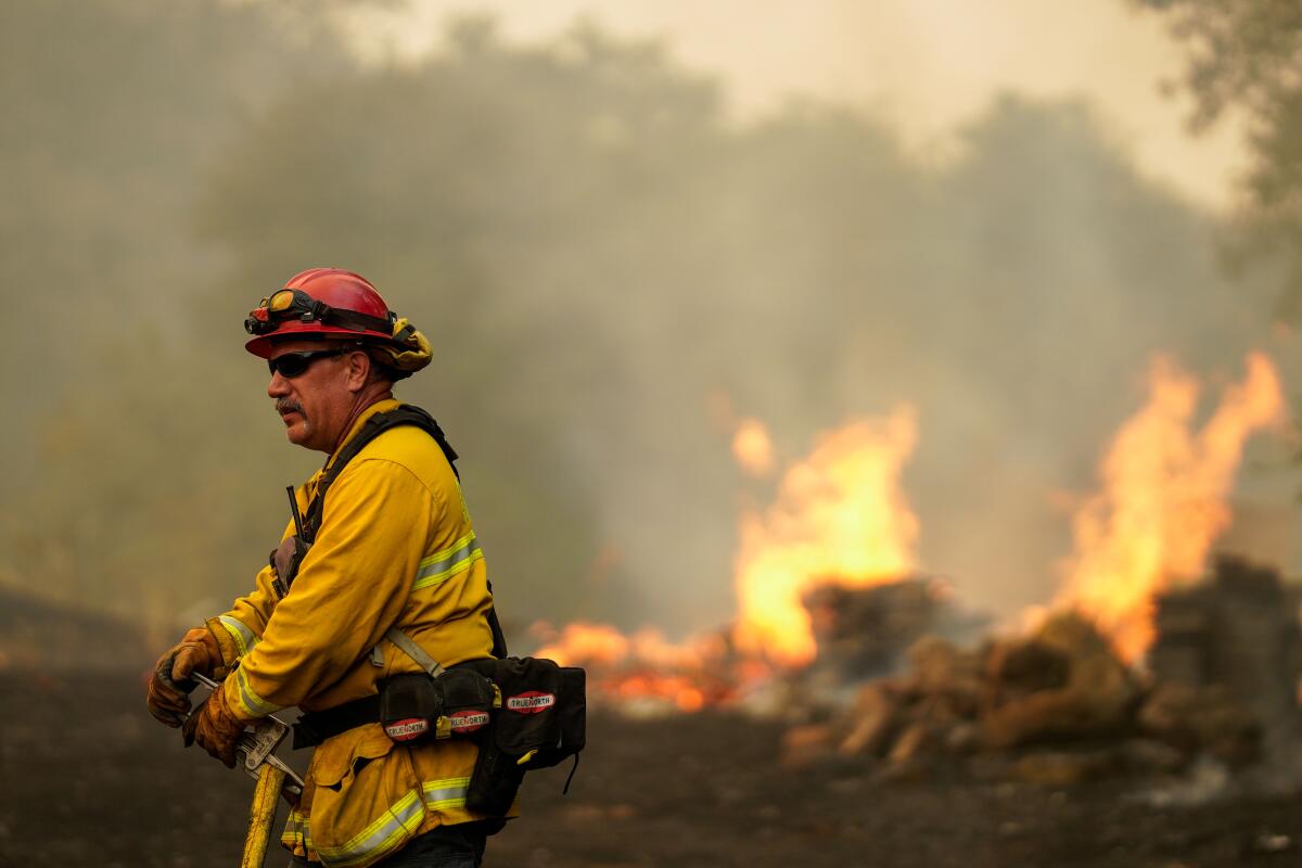 Flames leap in the background as a firefighter battles the Hennessy fire in Vacaville, Calif.