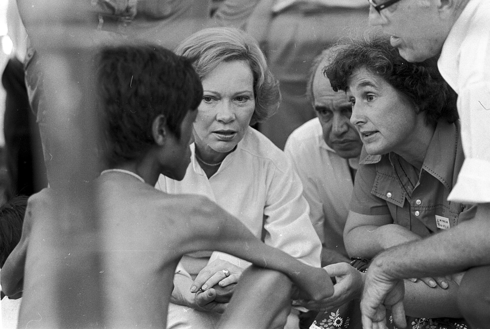 A thin Cambodian refugee speaks to a group of people including Rosalynn Carter.