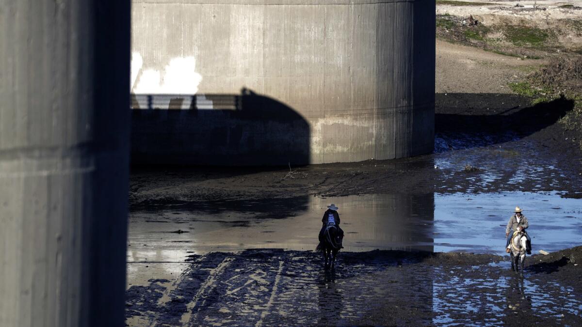 Men ride horseback in the shadow of Whittier Narrows Dam, which Army Corp of Engineers officials say no longer meets their tolerable-risk guidelines.