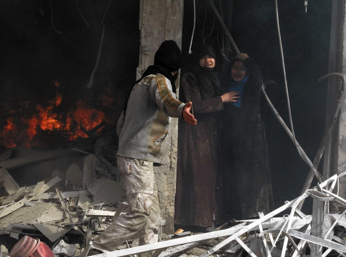 A man shows the way to two Syrian women as they leave a gutted building after an airstrike in Aleppo.
