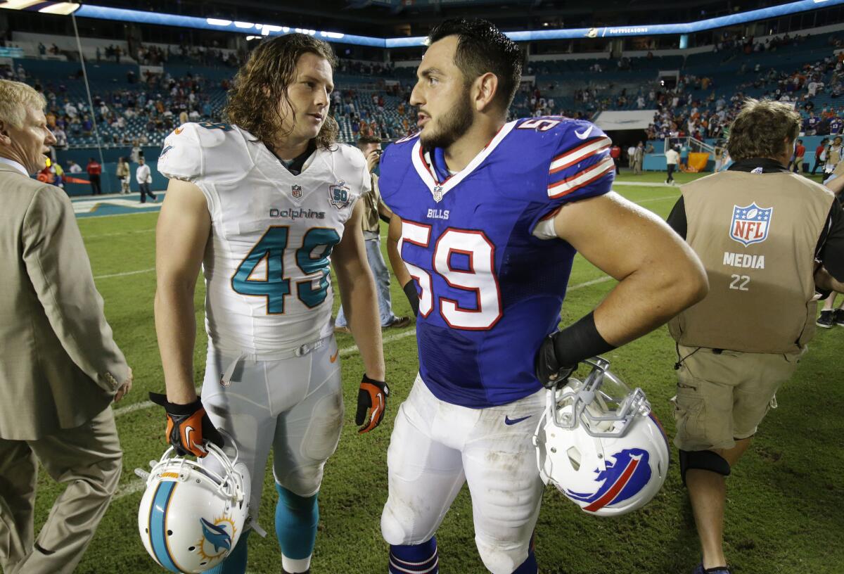 Buffalo Bills linebacker A.J. Tarpley (59) talks with Miami Dolphins linebacker Zach Vigil at the end of an NFL game last season, Tarpley's first year in the league. Citing fears over long-term brain damage from concussions, he recently retired.