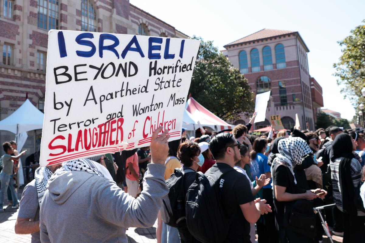 A protest march, one sign reading, "Israeli beyond horrified by apartheid state terror and wanton mass slaughter of children"